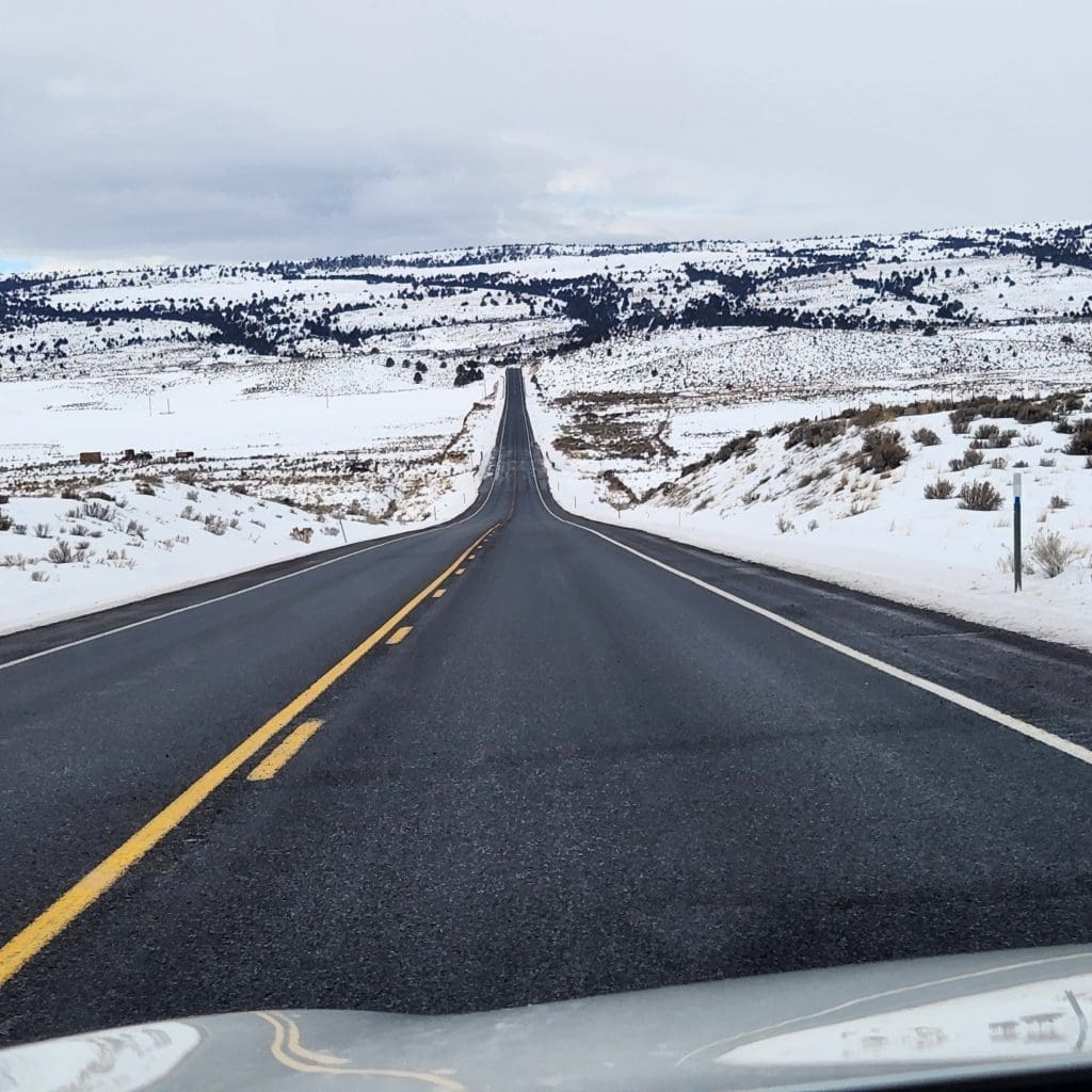 Open road with snow on either side of the road, giving a sense of freedom as a health benefit of healthy camping